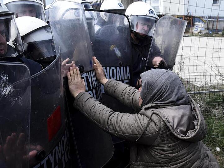 Eine Frau und Polizisten der Bereitschaftspolizei stoßen vor einem Flüchtlingslager westlich von Thessaloniki aufeinander.
