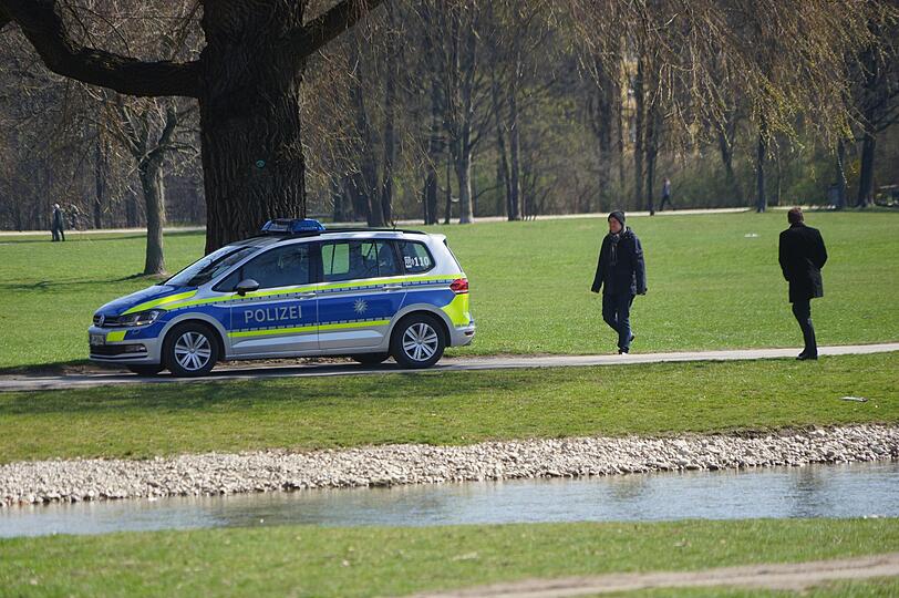 Polizei und Passanten im Englischen Garten am Schwabinger Bach in München.