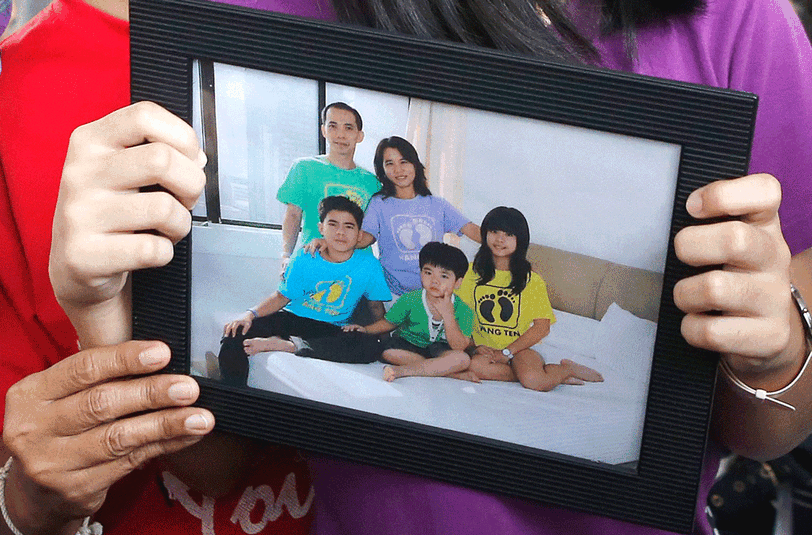 Eine Frau hält auf dem Flughafen von Surabaya ein Foto der Familie Tanus in die Kamera. Herumanto Tanus war mit seiner Frau und den beiden Söhnen an Bord von AirAsia-Flug QZ8501.