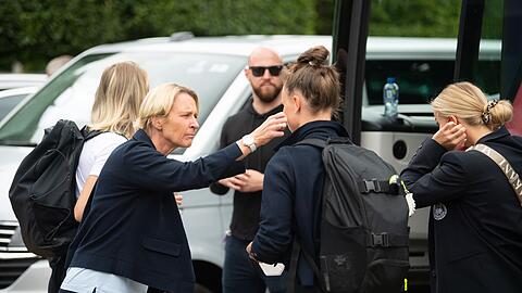 Bundestrainerin Martina Voss-Tecklenburg (l) versucht Spielerinnen bei der Abreise aufzumuntern.