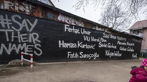 Ein kleines Mädchen schaukelt vor der Wand eines Jugendzentrums, auf dem die Namen der Opfer des Anschlags vom 19. Februar geschrieben stehen.