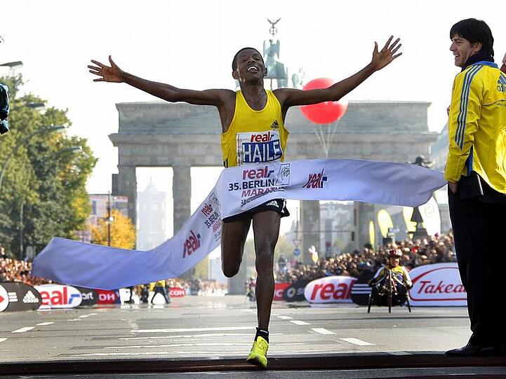 Jubelnd läuft Gebrselassie unter den Augen von Bundestrainer Löw (r) ins Ziel.