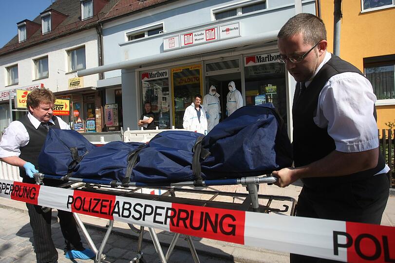 Bestatter tragen am Samstag eine Leiche aus einem Lottogeschäft in Nürnberg.