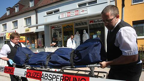 Bestatter tragen am Samstag eine Leiche aus einem Lottogeschäft in Nürnberg.
