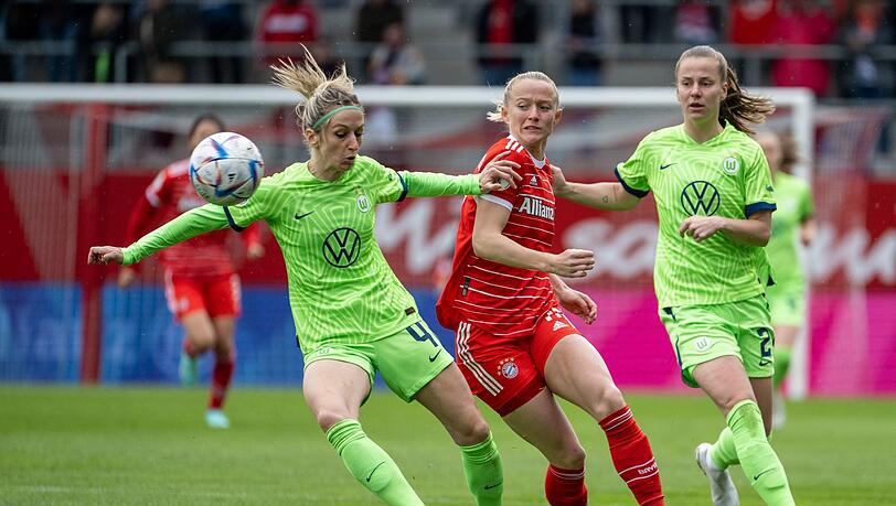 Die Wolfsburgerinnen Kathrin Hendrich (l) und Lynn Wilms (r) und Münchens Lea Schüller kämpfen um den Ball.