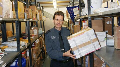 Der Zollbeamte Thomas Meister zieht im Hauptzollamt in Garching-Hochbrück eines der vielen Packerl aus dem Regal, die hier ankommen.