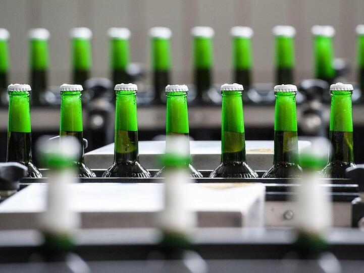 Flaschen mit Bier werden in der Abfüllanlage auf einem Förderband transportiert. Foto: Armin Weigel/Archiv