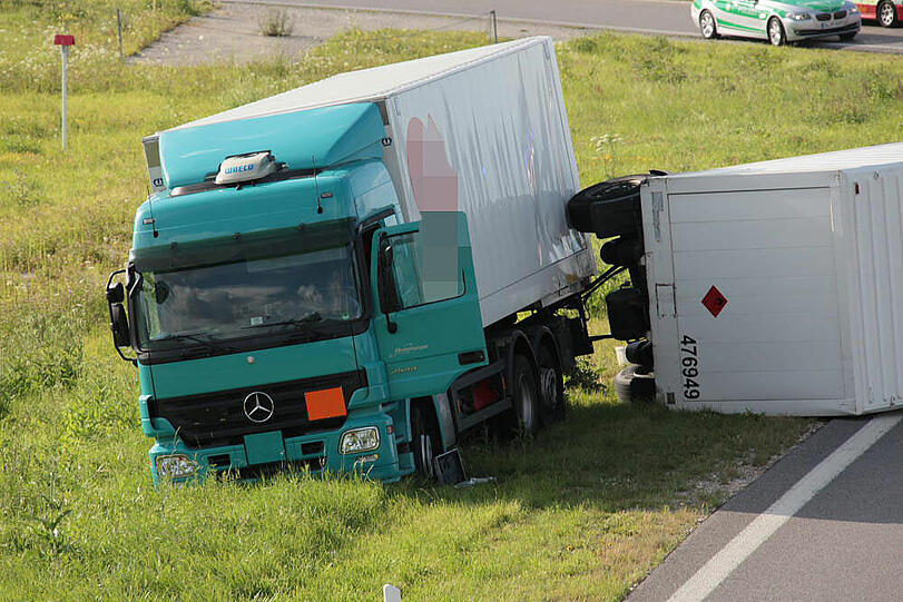 Vermutlich weil er zu schnell auf die Autobahn fährt, kommt ein Laster in der Kurve von der Fahrbahn ab und fährt in die Leitplanke. Sein Hänger kippt um.