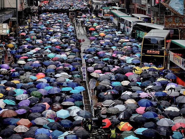 Regierungsfeindliche Demonstranten mit Regenschirmen nehmen an einem Marsch teil und beeinträchtigen damit den Verkehr.