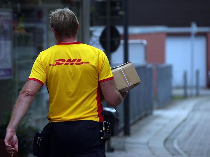 Ein DHL-Mitarbeiter liefert ein Paket aus.