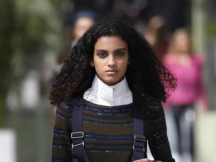 Ein Model trägt ein Outfit mit hohem weißem Vatermüörderkragen, der an Karl Lagerfeld erinnert.