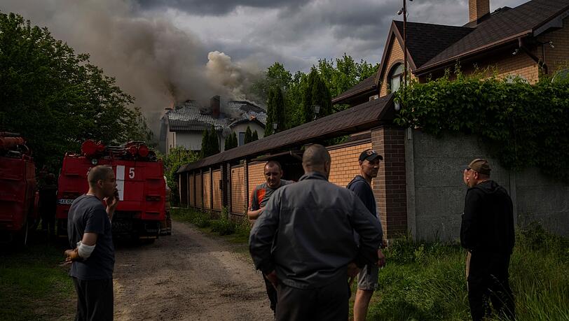 Nachbarn versammeln sich in Charkiw um ein brennendes Haus, das bei einem russischen Angriff mit Streumunition getroffen wurde. Nachbarn versammeln sich in Charkiw um ein brennendes Haus, das bei einem russischen Angriff mit Streumunition getroffen wurde.