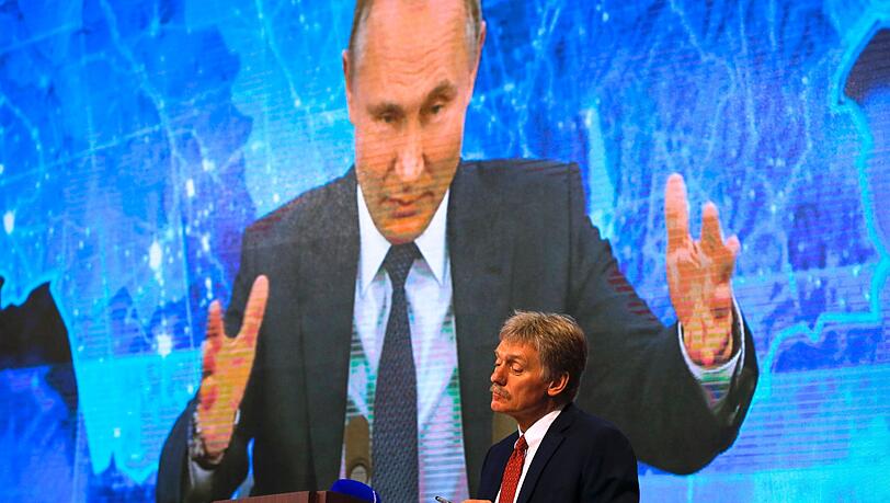 Russlands Präsident Wladimir Putin ist auf einem Bildschirm zu sehen, im Vordergrund steht sein Sprecher Dmitri Peskow (Archivbild). Beide heben das große militärische Potenzial Moskaus hervor.