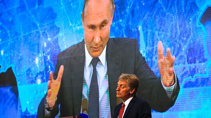 Russlands Präsident Wladimir Putin ist auf einem Bildschirm zu sehen, im Vordergrund steht sein Sprecher Dmitri Peskow (Archivbild). Beide heben das große militärische Potenzial Moskaus hervor.
