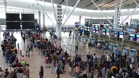 Reisende stehen am Flughafen in Kapstadt in langen Schlangen an den wenigen Schaltern an, die überhaupt noch offen sind.