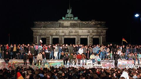 Ein Bild, das um die Welt ging: Jubelnde Menschen sitzen am 9. November 1989 auf der Mauer am Brandenburger Tor.