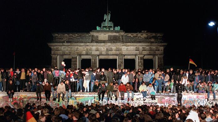 Ein Bild, das um die Welt ging: Jubelnde Menschen sitzen am 9. November 1989 auf der Mauer am Brandenburger Tor.