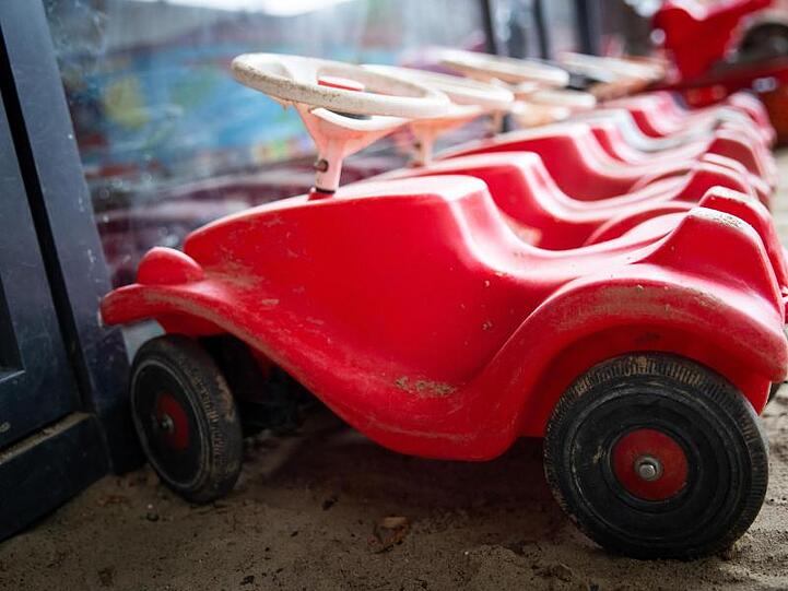 Mehrere Bobbycars stehen auf dem Gelände eines Kindergartens. Foto: Christian Charisius/dpa/Archivbild