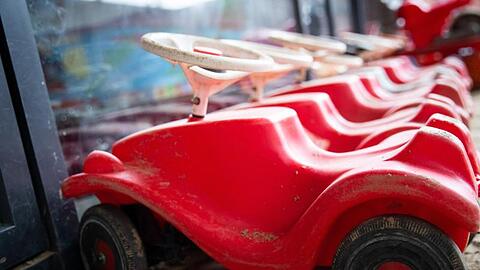 Mehrere Bobbycars stehen auf dem Gelände eines Kindergartens. Foto: Christian Charisius/dpa/Archivbild