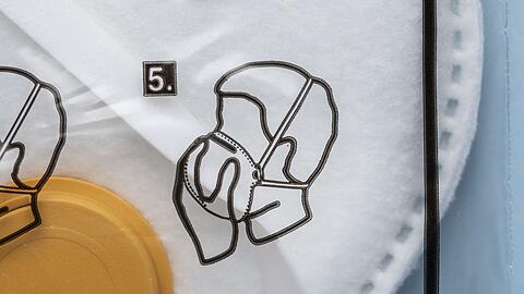 Anleitung für das korrekte Aufsetzen der Maske auf der Verpackung einer FFP3-Atemschutzmaske. (Symbolbild)