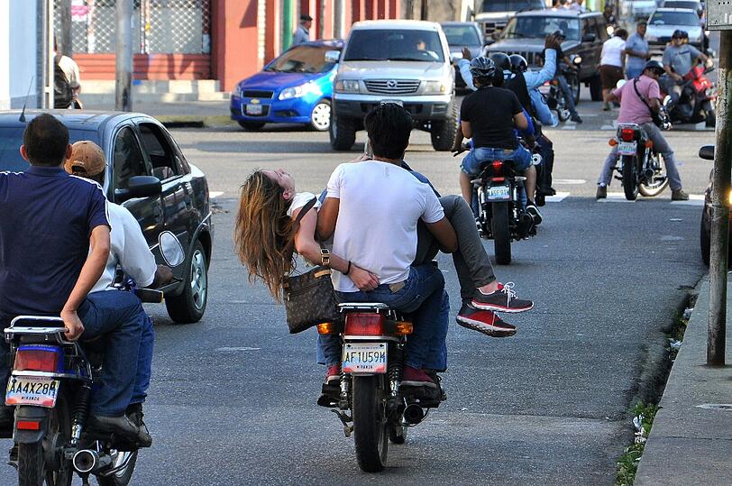 Brutale Szene: Ein Mann trägt eine Frau auf den Armen und fährt dabei Motorrad. Sie hat eine Kugel im Kopf!