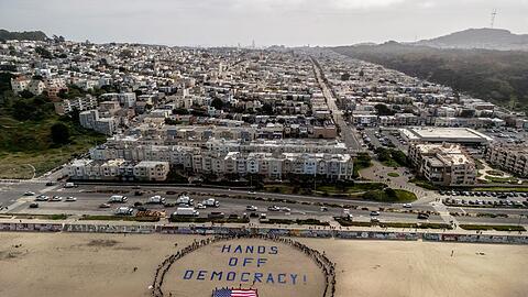 An einem Strand im Bundesstaat Kalifornien bildeten Demonstranten einen menschlichen Kreis um eine US-Flagge und den Slogan "Hände weg von der Demokratie!".