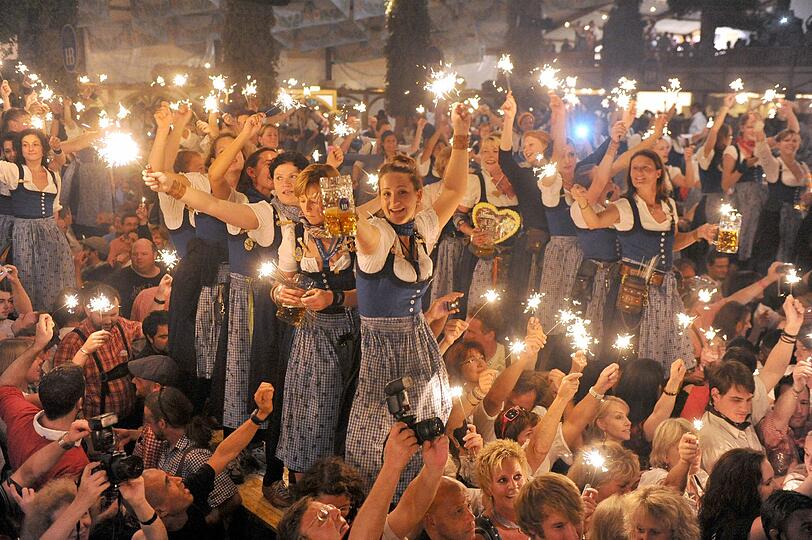 Sternwerfer, gedimmtes Licht und ein bisschen Wehmut: Am letzten Wiesn-Abend dürfen auch die Bedienungen auf die Bänke.