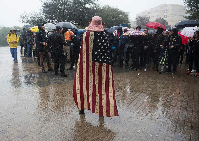 Eine Frau trägt bei einer Demonstration eine Fahne über den Schultern.