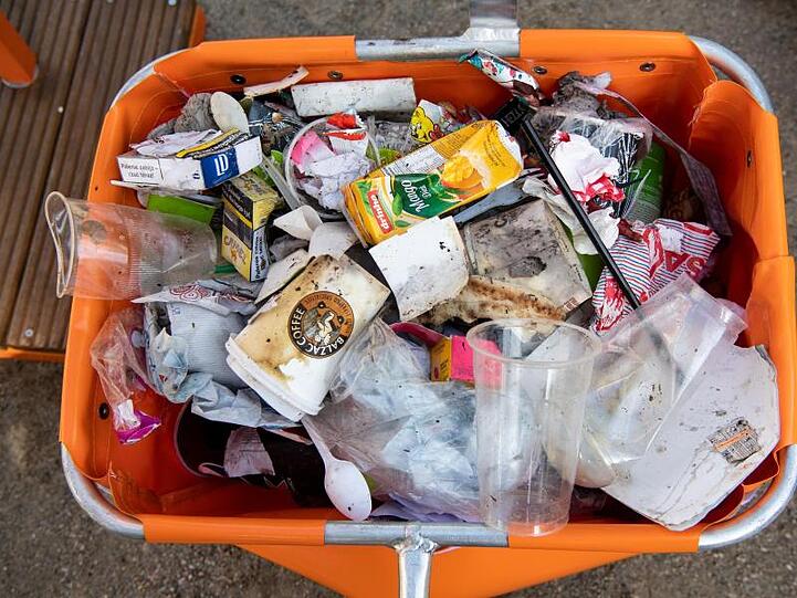 Inhalt einer Straßenmülltonne mit zahlreichen Verpackungen, Einwegbechern und Restmüll.