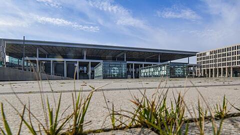Gras wächst zwischen den Fugen auf einem Platz vor dem Terminal des Hauptstadtflughafens BER.