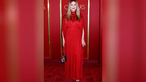 Rita Wilson strahlt in ihrer roten Abendrobe.