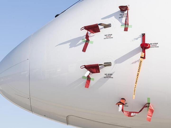 Bänder mit der Aufschrift "Remove Before Flight" (dt. Vor dem Flug entfernen) sind an einem Flugzeug der Schweizer Fluggesellschaft Swiss befestigt.