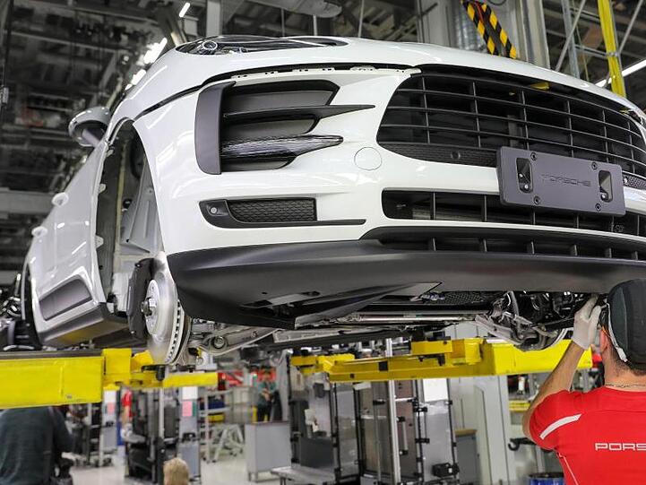 Ein Mitarbeiter arbeitet in der Montage an einem Porsche Macan im Werk Leipzig.