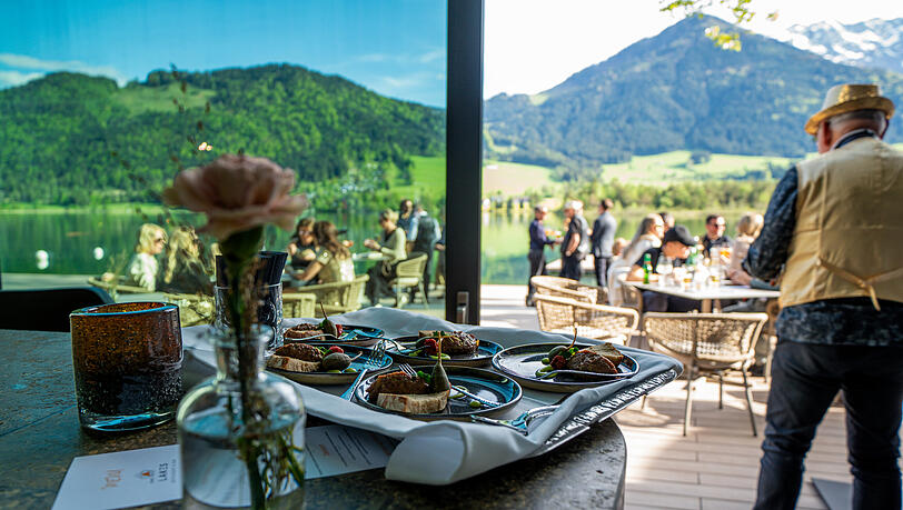 Das Lakes mit Terrasse und außergewöhnlicher Architektur lädt zum Genießen erlesener Getränke und verschiedenster Events in der Abendsonne mit Blick auf den See und das Kaisergebirge ein.