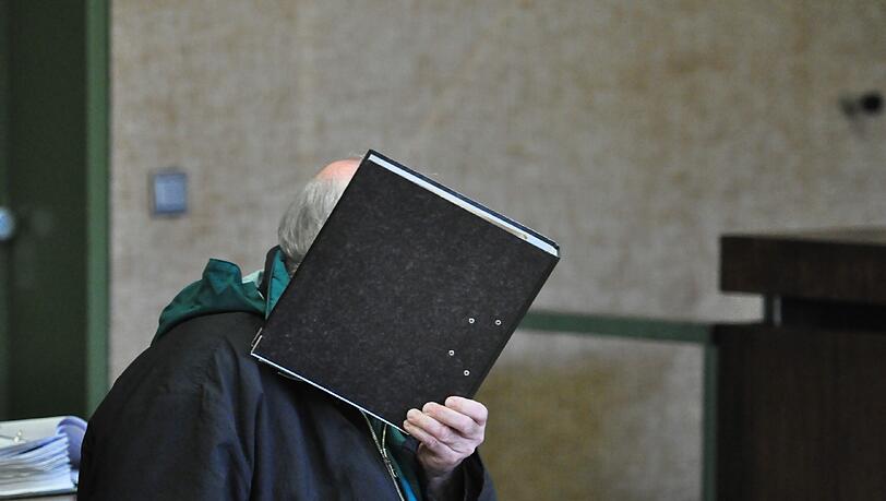 Der Kinderschädner Joachim R. (59) versteckt sein Gesicht hinter einem Aktenordner.