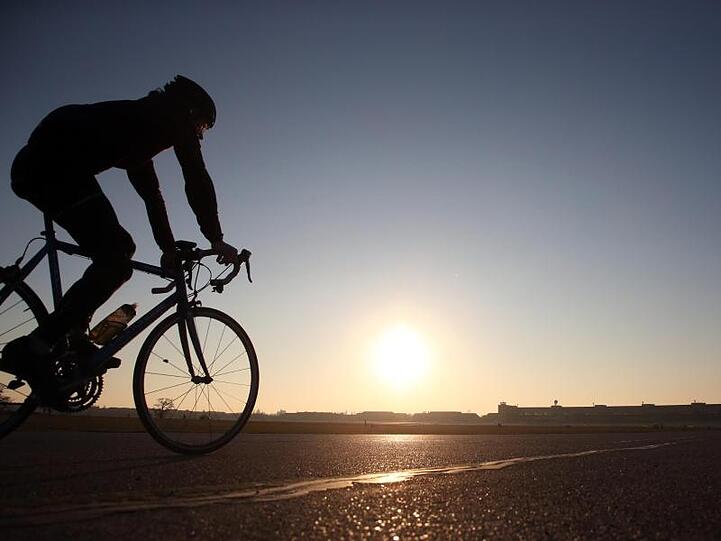 Bei untergehender Sonne zieht ein Radrennfahrer auf dem Flughafen Berlin-Tempelhof seine Runden.