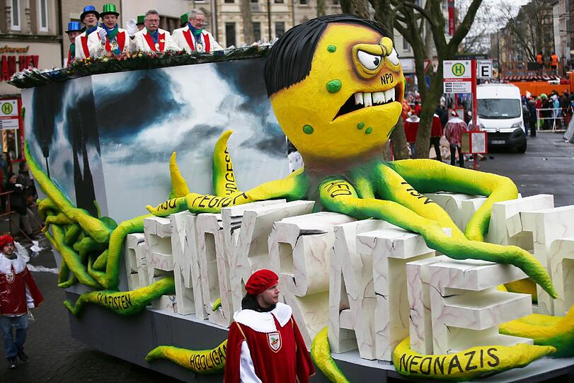 Karnevalisten ziehen am Rosenmontag mit einem Motivwagen, der eine Demokratiefressende Krake zeigt, durch Köln.