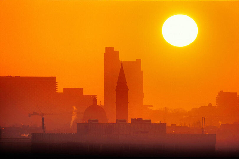 Einzigartiges Natur-Schauspiel: Sahara-Staub beim Sonnenaufgang über München. Hier der Blick auf Hypovereinsbank, Arabellapark, Kirche St. Ursula Schwabing und Schwabinger Dom.