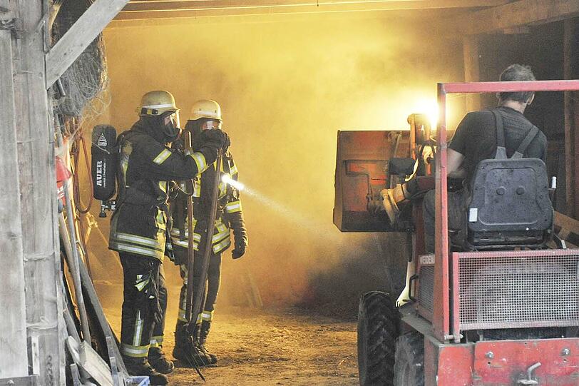 Flammen schlagen aus einem Strohlager: Die Feuerwehr versucht, den Brand in den Griff zu bekommen