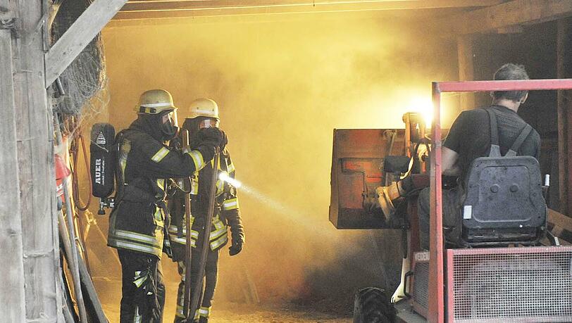 Flammen schlagen aus einem Strohlager: Die Feuerwehr versucht, den Brand in den Griff zu bekommen Flammen schlagen aus einem Strohlager: Die Feuerwehr versucht, den Brand in den Griff zu bekommen