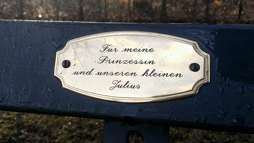 Im Englischen Garten und Nymphenburger Schlosspark haben Münchner tausende Plaketten mit Widmungen auf Parkbänken angebracht.
