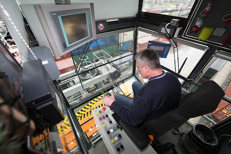 An den Joystick darf nur er: Kranführer Herr Jacob hebt hoch oben in seiner Kran-Kabine einen Container an.