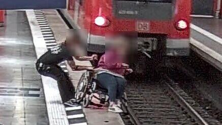 Der Moment der Rettung: Jürgen Hermann zieht die Rollstuhlfahrerin vom Gleis.
