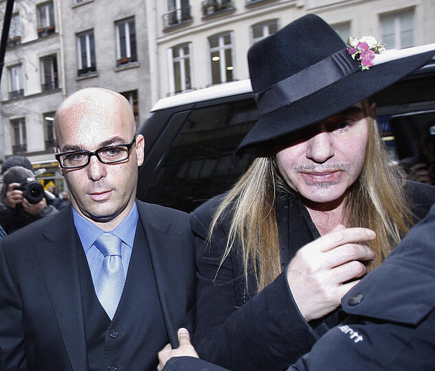 Bislang leugnet er die Vorwürfe: Designer John Galliano (r.) auf dem Weg zur Polizeistation.
