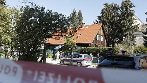Polizisten in Graz stehen vor dem Wohnhaus, in dem eine 39-Jährige getötet wurde.