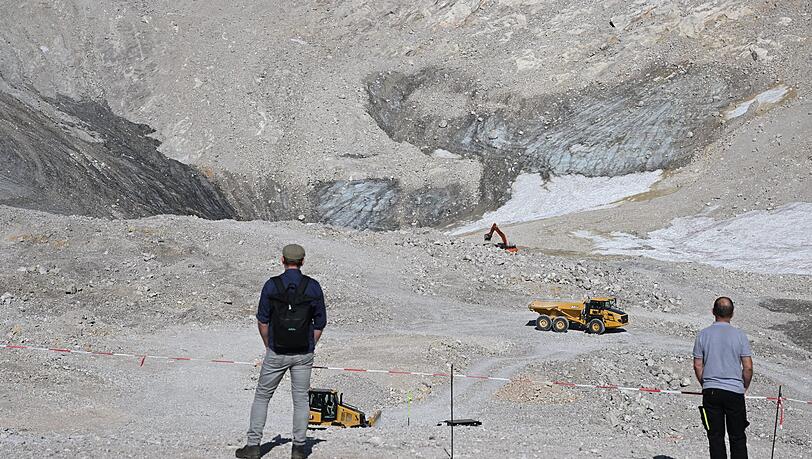 Wanderer beobachten Baumaschinen neben den Überresten des Nördlichen Schneeferner-Gletschers auf der Zugspitze. (Archivbild) Wanderer beobachten Baumaschinen neben den Überresten des Nördlichen Schneeferner-Gletschers auf der Zugspitze. (Archivbild)