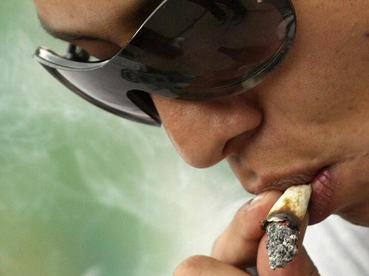 Ein junger Mann raucht einen Joint.