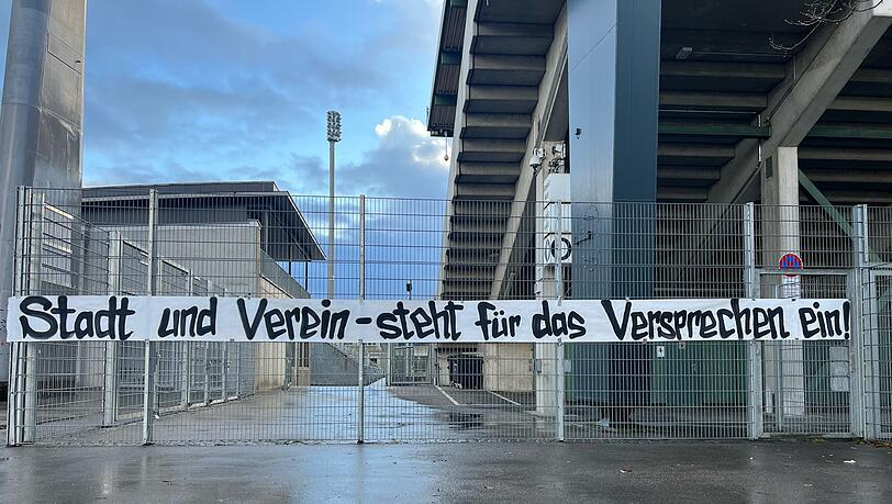 Ein Banner der Initiative "Sechzig im Sechzger" mit der Aufschrift "Stadt und Verein – steht für das Versprechen ein!" hängt am Zaun vor dem Grünwalder Stadion. Ein Banner der Initiative "Sechzig im Sechzger" mit der Aufschrift "Stadt und Verein – steht für das Versprechen ein!" hängt am Zaun vor dem Grünwalder Stadion.