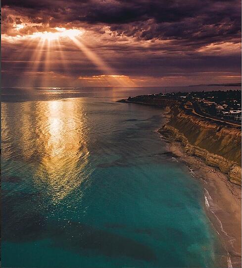 Die Sonne kämpft sich durch die Wolken an der Küste von Port Willunga.