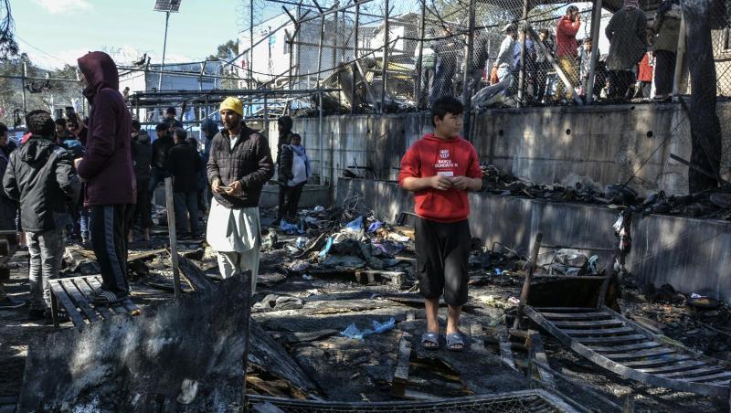 Flüchtlinge stehen im Lager Moria auf den abgebrannten Überresten eines Containerhauses. Flüchtlinge stehen im Lager Moria auf den abgebrannten Überresten eines Containerhauses.